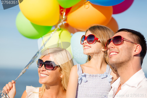 Image of happy family with colorful balloons outdoors
