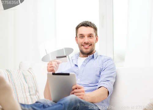 Image of smiling man working with tablet pc at home