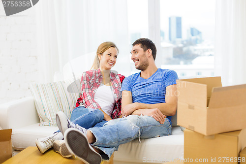 Image of smiling couple relaxing on sofa in new home