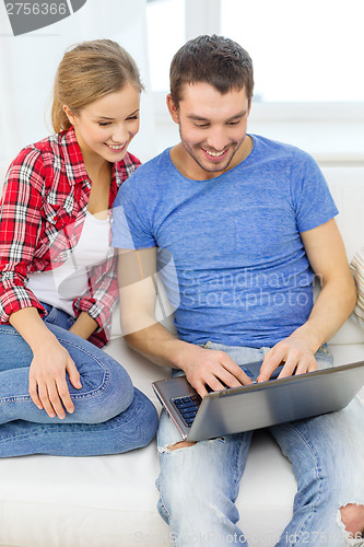 Image of smiling couple with laptop computer at home