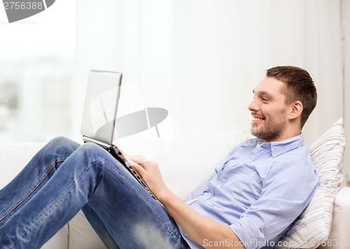 Image of smiling man working with laptop at home