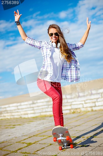 Image of smiling teenage girl riding skate outside