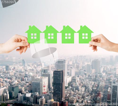 Image of man and woman hands with many green paper houses