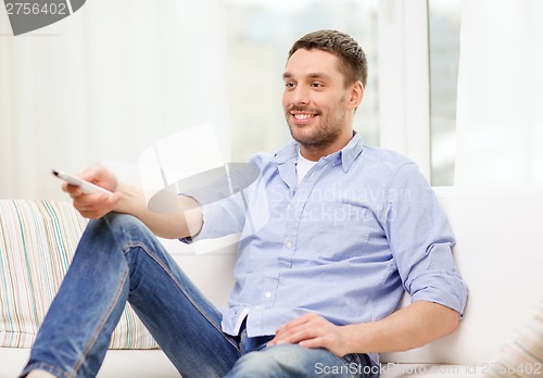 Image of smiling man with tv remote control at home