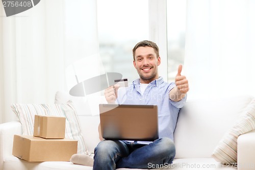 Image of man with laptop, credit card and cardboard boxes