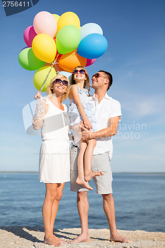 Image of happy family with colorful balloons at seaside