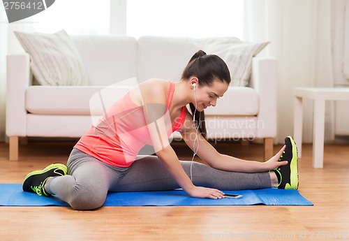 Image of smiling teenage girl streching on floor at home