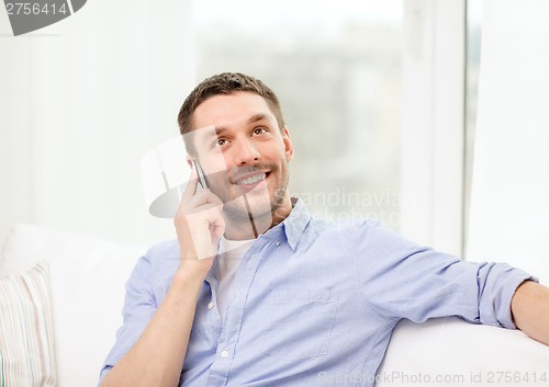 Image of smiling man with smartphone at home