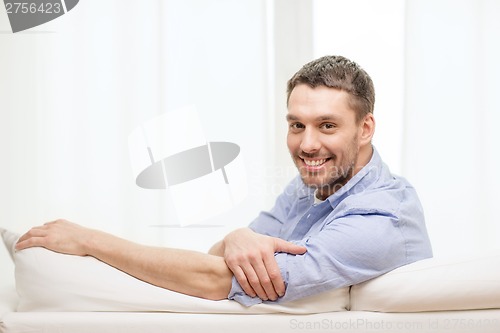 Image of smiling man sitting on sofa at home