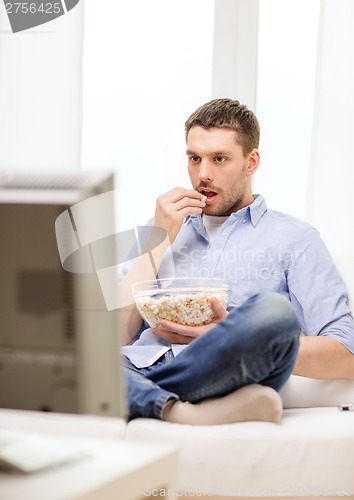 Image of smiling man watching sports at home