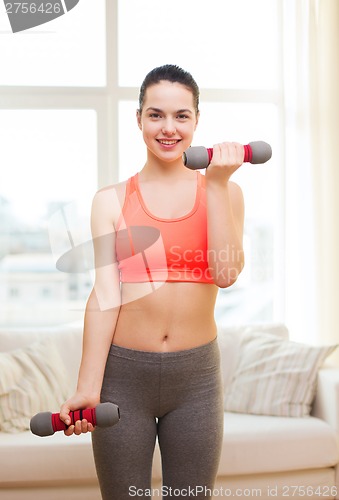 Image of smiling teenage girl exercising with dumbbells