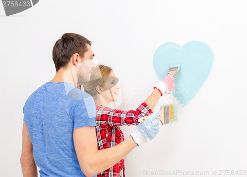 Image of smiling couple painting small heart on wall