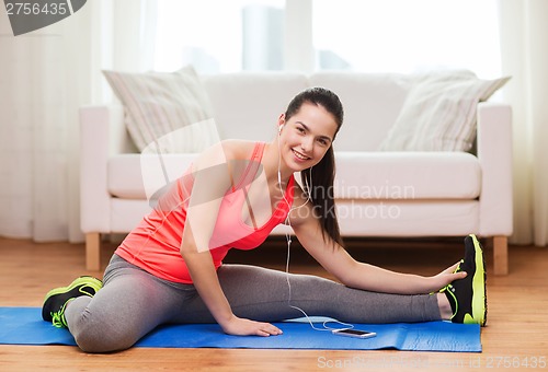 Image of smiling teenage girl streching on floor at home