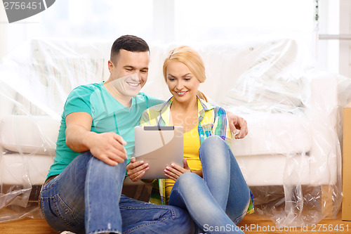 Image of smiling couple with tablet pc in new home