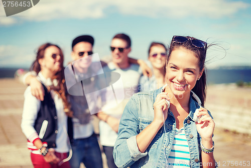 Image of teenage girl with headphones and friends outside