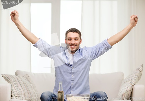 Image of smiling man watching sports at home