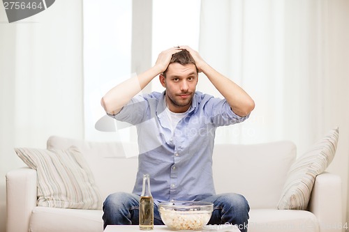 Image of sad man watching sports at home