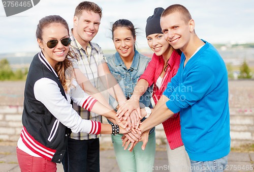 Image of teenagers hands on top of each other outdoors