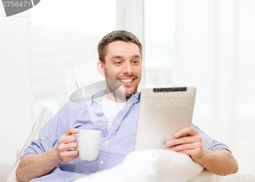Image of smiling man working with tablet pc at home