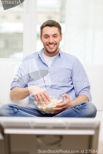 Image of smiling man watching sports at home