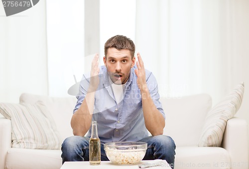 Image of sad man watching sports at home