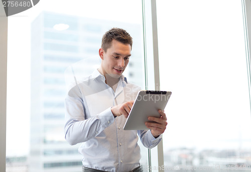 Image of smiling businessman with tablet pc in office