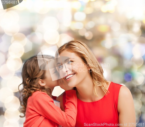 Image of smiling mother and daughter whispering gossip