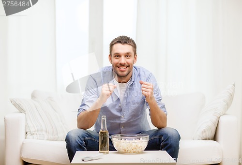 Image of smiling man watching sports at home