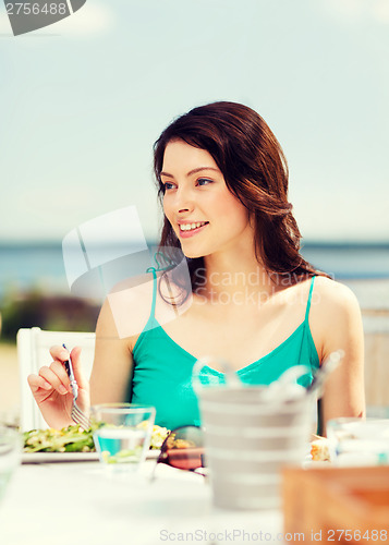 Image of girl eating in cafe on the beach