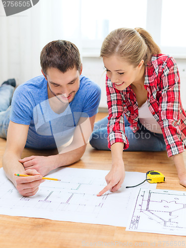 Image of smiling couple looking at blueprint at home