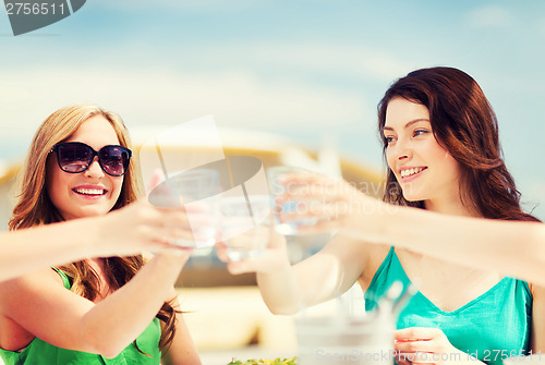 Image of girls making a toast in cafe on the beach