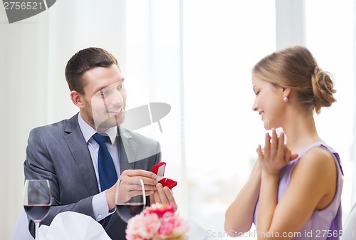 Image of man proposing to his girlfriend at restaurant