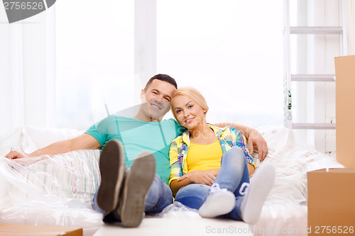 Image of smiling couple relaxing on sofa in new home