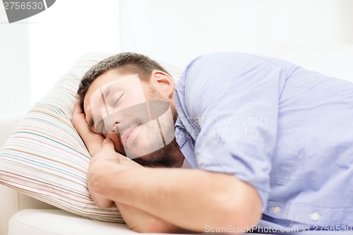 Image of calm young man lying on sofa at home