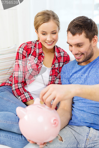 Image of smiling couple with piggybank sitting on sofa