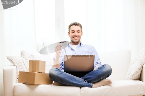 Image of man with laptop, credit card and cardboard boxes