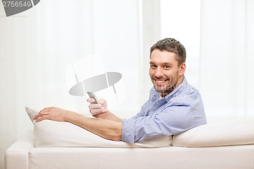 Image of smiling man with smartphone at home