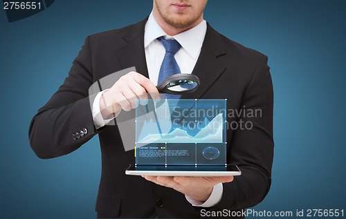 Image of businessman hand holding magnifier over tablet pc