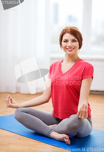 Image of smiling redhead teenager meditating at home