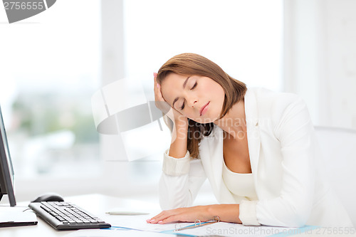 Image of tired businesswoman with computer and papers