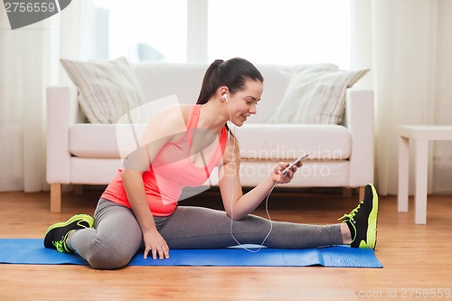 Image of smiling teenage girl streching on floor at home