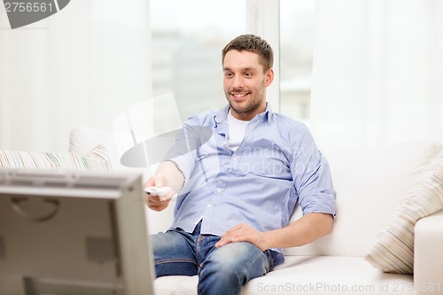 Image of smiling man with tv remote control at home