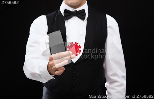 Image of dealer holding red poker chip