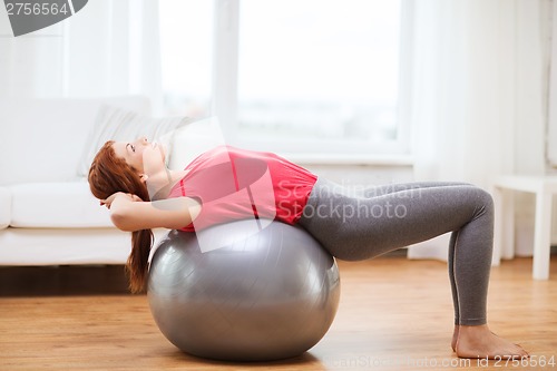 Image of smiling redhead girl exercising with fitness ball