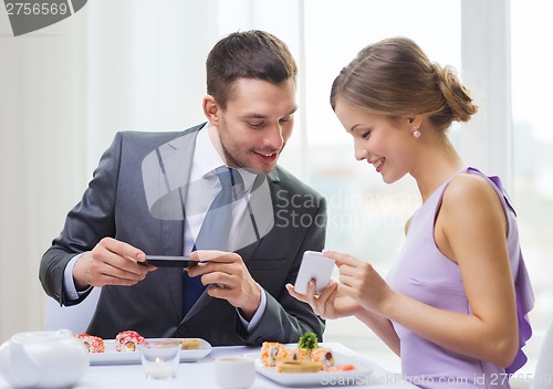 Image of smiling couple with sushi and smartphones