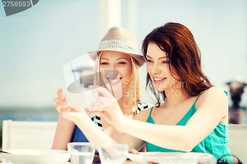 Image of girls taking photo in cafe on the beach