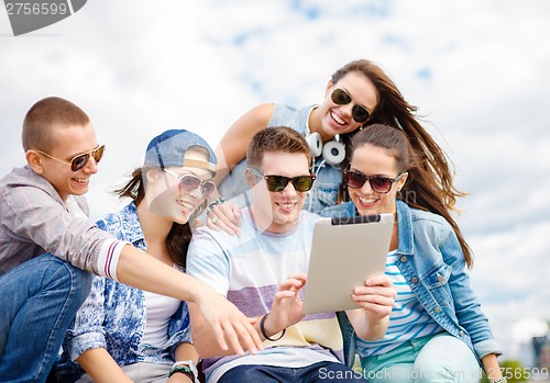 Image of group of smiling teenagers looking at tablet pc