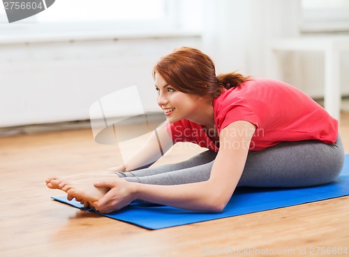 Image of smiling teenage girl streching on floor at home