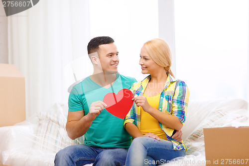 Image of smiling couple with red heart on sofa in new home