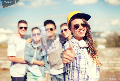 Image of teenage girl with headphones and friends outside